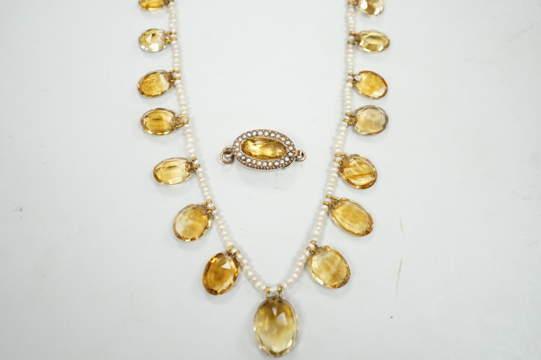 An Edwardian twenty one graduated oval cut citrine set seed pearl necklace (a.f) clasp loose, approx. 34cm.